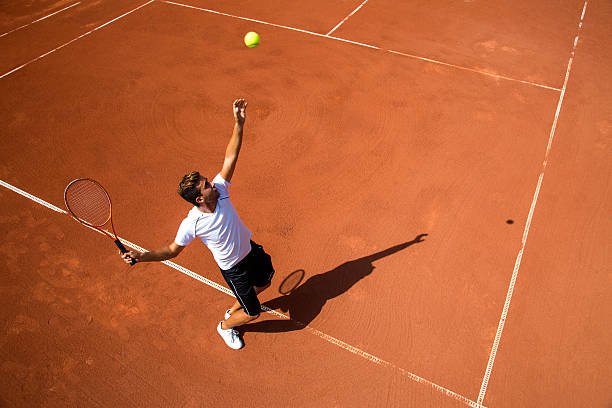 Joueur de tennis au service sur terre battue